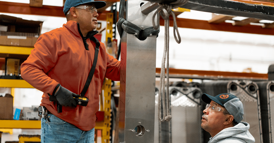 Two men work on plate heat exchanger frame